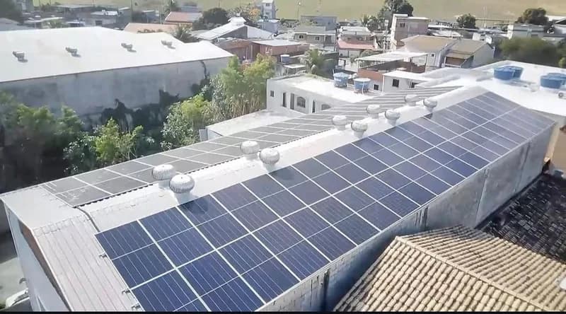 Vista aérea de galpão comercial com telhado metálico coberto por painéis solares